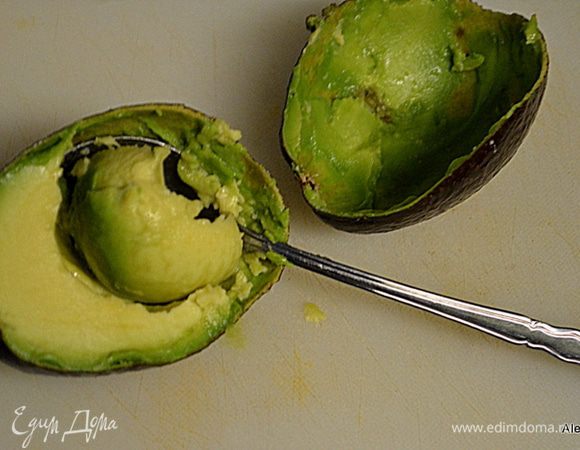 Разрезать авокадо на две части ножом. Очистить от кожуры.
