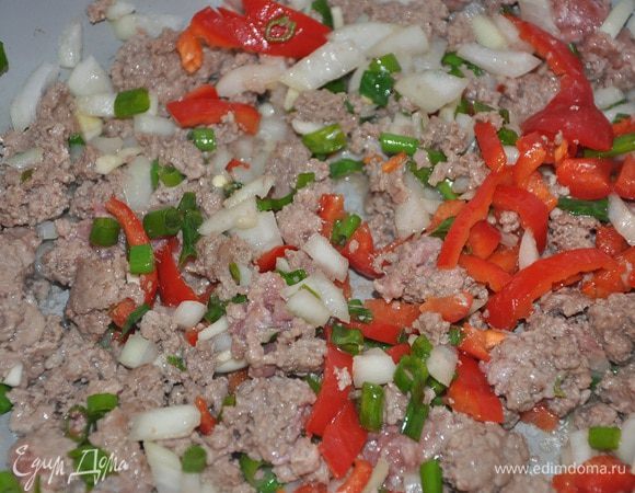 Тем временем подготовим фарш, для этого разогреть в глубокой сковороде масло добавить говядину, лук, зеленый лук, чеснок, и перец обжарить пока мясо не подрумяниться, а овощи не станут мягкими.