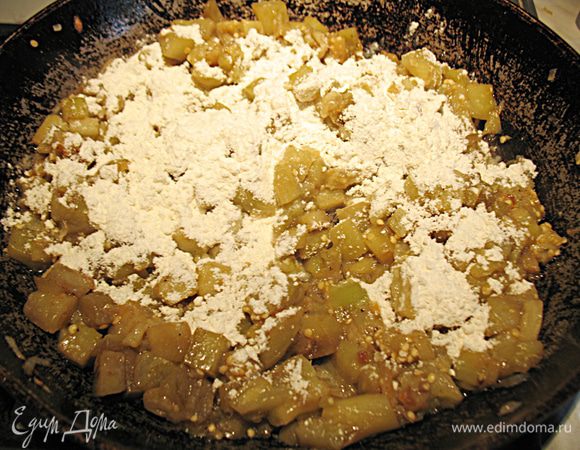 Через пять минут к баклажанам с луком добавляем муку и перемешиваем. 