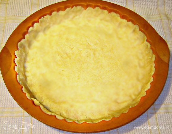 Охлаждённое тесто выкладываем сразу в форму, подушечками пальцев равномерно распределяя тесто и формируя бортики. Тесто слишком рассыпчатое, чтобы его предварительно раскатать и перенести в форму.