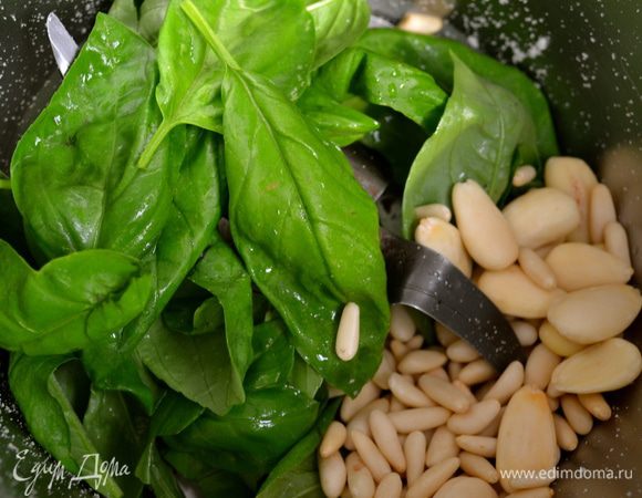 Тем временем положить в чашу миксере вымытые и высушенные листья базилика, кедровые орешки, миндаль... 