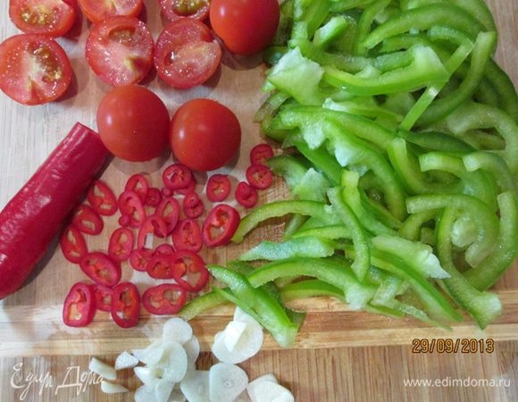 Овощи вымыть. Помидоры разрезать пополам. У перцев удалить сердцевинки. Сладкий перец нарезать соломкой, острый - кольцами. Чеснок тонко нарезать.
