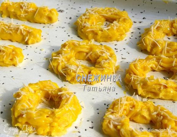 На противень, смазанный сливочным маслом, отсаживаем тесто из кулинарного мешка в виде колец, можно и другой формы, несколько штук я сделала в виде палочек. Смазываем заготовки желтком и посыпаем натёртым сыром.