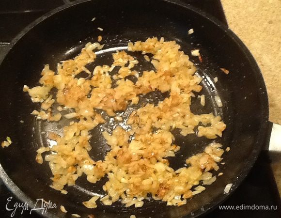 Разогреть сковороду, добавить 2 столовые ложки оливкового масла. Добавить лук репчатый и чеснок и жарить на слабом огне около 3 минут или до золотистого цвета, периодически помешивая.