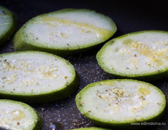 Цукини нарезаем на ломтики толщиной примерно 1 см. Выкладываем на противень или в форму, солим, добавляем немного орегано, сбрызгиваем оливковым маслом и ставим в духовку при 220-240 С. Через 5 минут переворачиваем.