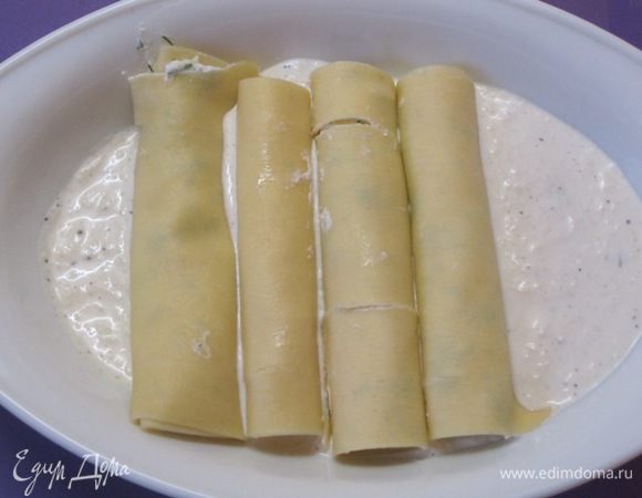 Половину массы вылить на дно смазанной жиром формы, выложить каннелони.