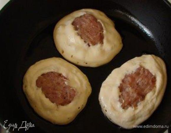 На сковороде разогрейте масло. Ложкой выложите тесто для беляшей, на тесто — фарш, на фарш снова немного теста. Должны остаться небольшие отверстия. Тесто на кефире хорошо прожаривается и не растекается. 