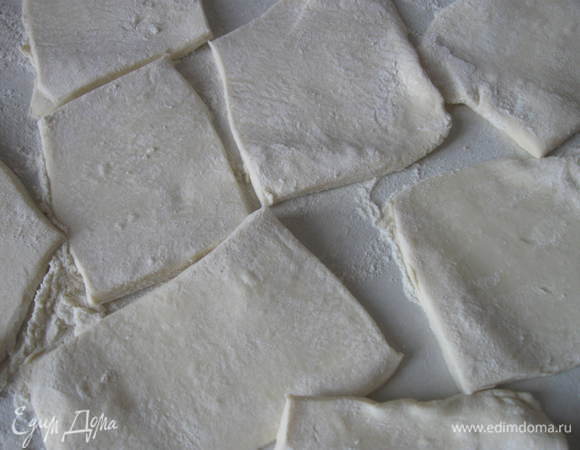 Тесто  разморозить, раскатать в более тонкий пласт. Разрезать на прямоугольные кусочки. Положить кусочки теста на противень, застеленный бумагой для выпечки.

