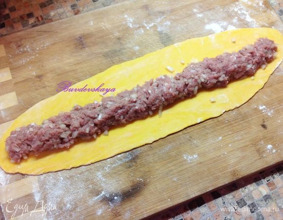 На присыпанной мукой поверхности раскатать тесто и разрезать на 4 широкие полоски или скатать руками 4 колбаски и раскатать каждый из них скалкой. На центр каждой полоски выложить начинку по всей длине и аккуратно защипить края.