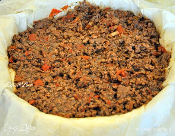 Каждый лист фило смазать оливковым маслом и уложить друг на друга в форму диаметром 24 см. Тесто должно сильно свисать по краям. На тесто выложить мясную начинку, 