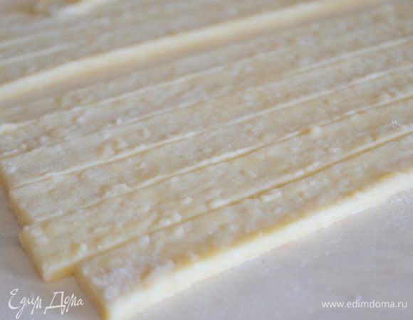 Тесто раскатать на столе, обильно присыпанном мукой. Нарезать на одинаковые полоски. Посыпать кунжутом по вкусу или травками. 