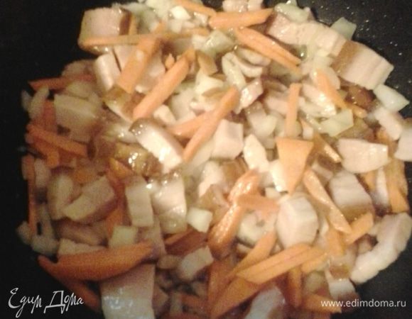 К бекону добавляем нарезанный кубико лук и нарезанную соломкой морковь, тушим 2–3 минуты.