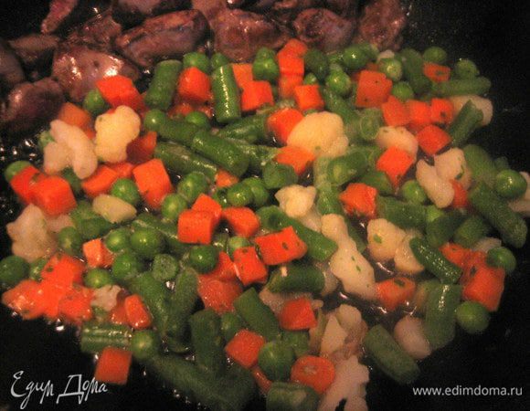 Отодвигаем лопаткой обжаренную печень и пристраиваем рядом половину пачки овощей.