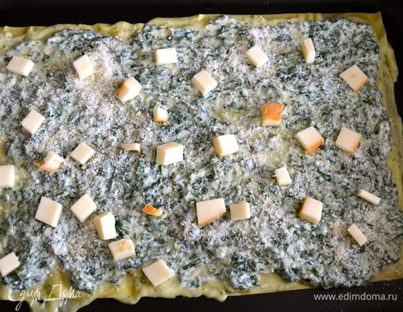 Сверху распределяем крем на рикотте со шпинатом. Присыпаем тертым сыром пармезан и выкладываем кубики копченого сыра.
