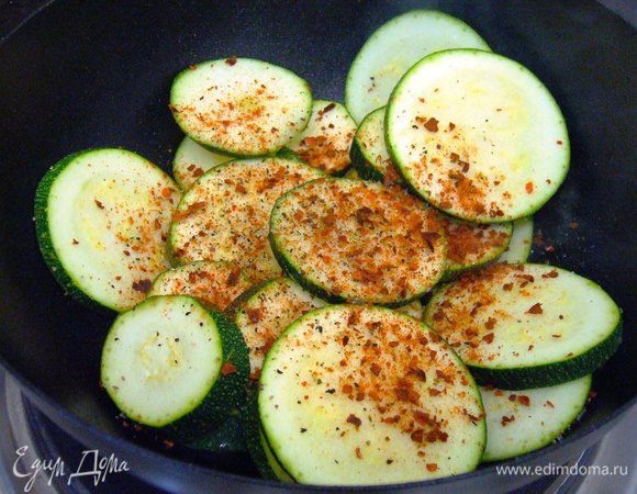 В разогретую сковороду вливаем оливковое масло, далее отправляем туда цуккини и специи. Обжариваем минуты 2-3.