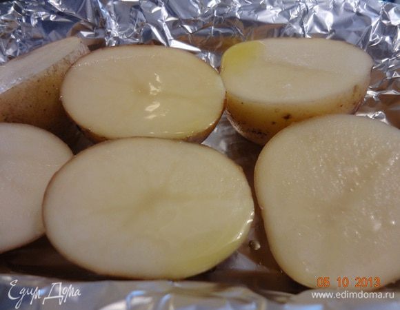 Для начала вымыть со щеткой картофель, не очищая, разрезать на две части. Форму застелить пищевой фольгой, выложить картофель, сбрызнуть оливковым маслом, можно посыпать солью и отправить в разогретую до 190 С духовку на час не меньше. Картофель внутри должен стать мягким.