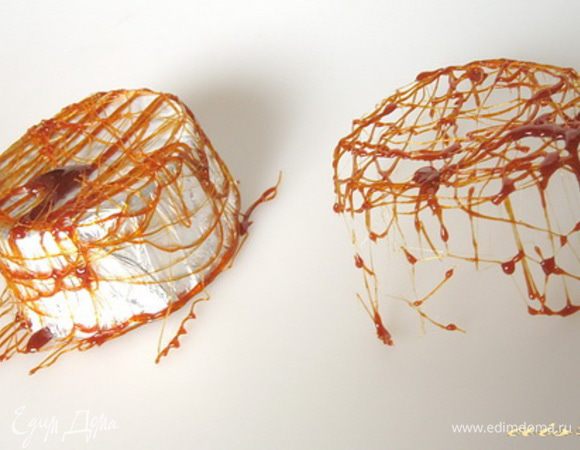 Теперь на небольшом огне растопить сахар, постоянно помешивая, чтобы получилась карамель. Дать ей немного остыть, чтобы она начала тянуться. Хаотически нанести рисунок на формочки, чтобы получилась карамельная сетка.
Дать карамели застыть и потом аккуратно снять ее с формочки из фольги.