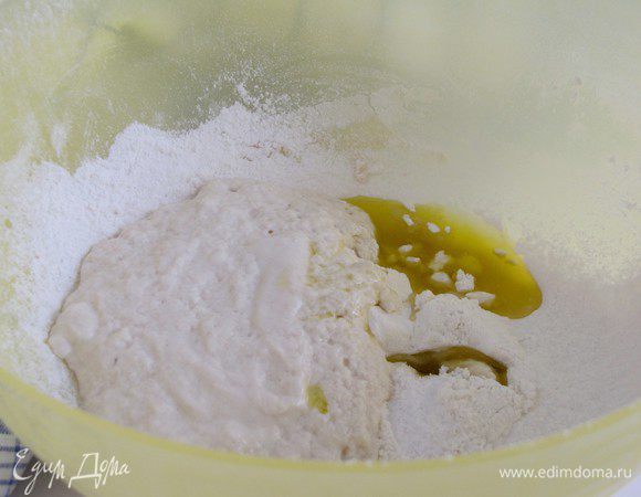 Просеять в миску оставшеюся  муку, добавить соль, оливковое масло и опару.