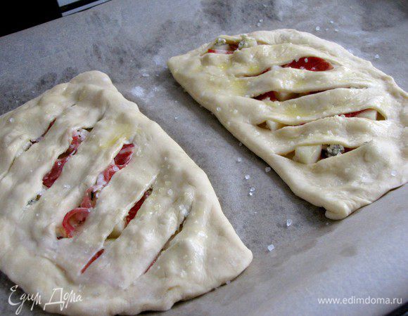 Завернуть край с надрезами на край с начинкой  и защипать. Выложить на противень, смазать оливковым маслом, немного посыпать крупной солью.