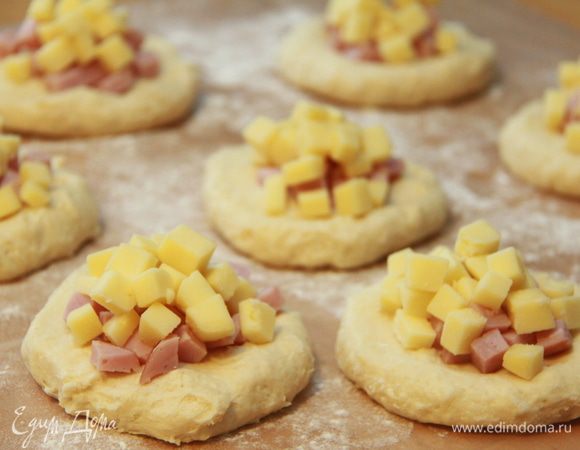 Через 1,5 часа тесто готово. Разделить тесто на 8 колобков. Каждый колобок расплющить в небольшую лепёшку. На каждую лепёшку положить начинку: ветчину и сыр. Я сразу распределила начинку на 16 частей, так удобнее выложить потом всё равномерно.