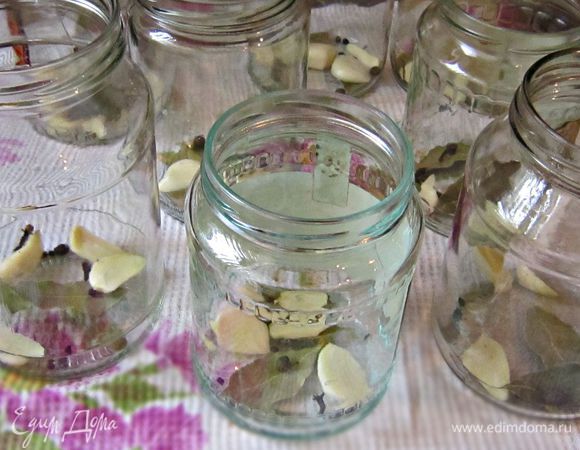 Простерилизовать банки. На дно каждой банки положить по 2-3 зубчика чеснока (можно разрезать пополам), по 3 горошины горького и душистого перца, 2 лавровых листочка и по 2-3 бутончика гвоздики. 
