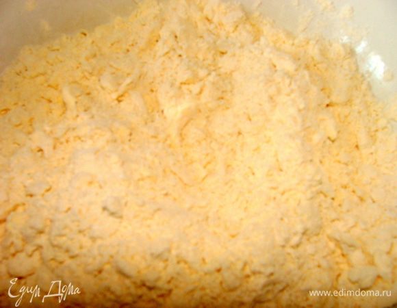 Добавьте муку и разрыхлитель. Все тщательно разомните руками до образования однородной крошки.