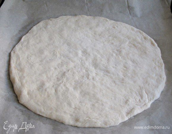 Когда тесто подойдет, разделить его на две части. Каждую часть раскатать в круг, толщиной 0,5 см. Выложить на противень, застеленный пекарской бумагой.