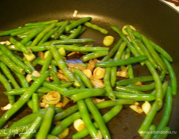Лук обжариваем несколько минут на оливковом масле до мягкости. Добавляем фасоль и готовим еще минуту.
