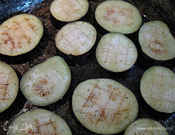 На кружочках баклажанов сделать неглубокие надрезы с двух сторон и смазать растительным маслом.  Выложить на противень поперчить. Запекать в разогретой до 200 градусов духовке минут 20-30, до готовности. 