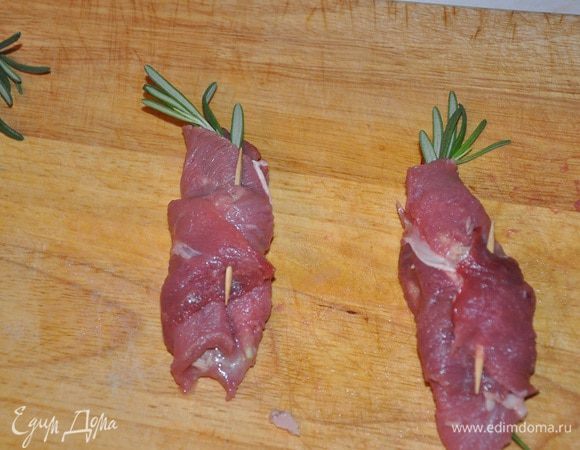 На каждый кусок мяса положить филе тунца, и веточку розмарина.
Свернуть в виде рулета и сколоть деревянными палочками.
