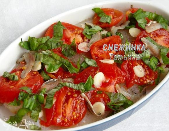 На рыбку в форму кладём кольца томатов, анчоусы, чеснок. Распределяем базилик.