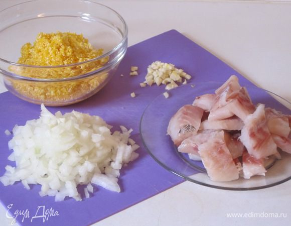 Кукурузную крупу тщательно промыть. Рыбное филе нарезать небольшими кусочками. Лук и чеснок мелко нарезать.