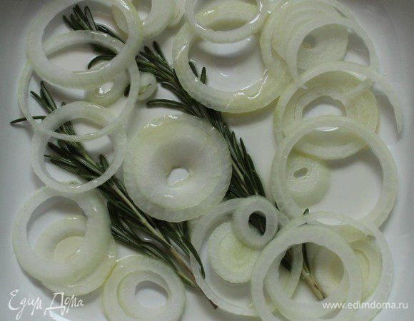 Луковицу нарезать тонкими кольцами. Форму для запекания смазать оливковым маслом, положить веточки розмарина и луковые кольца. Розмарин и лук  будут бороться с неприятностью №2 - со специфическим запахом.