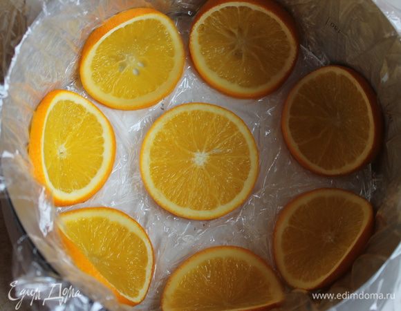 Когда апельсины будут готовы, даeм им остыть.  Возьмем форму 20см, если нет такой , то можно взять кольцо (как сделала я) и выстилить его пленкой. И берем наши кружочки выкладываем вот таким  образом,сгибаем их посередине, они будут гнуться очень хорошо. Примерно у мeня ушло 8 штук.Если же вы возьмете форму, то ее можно обмазать и обсыпать сахаром.