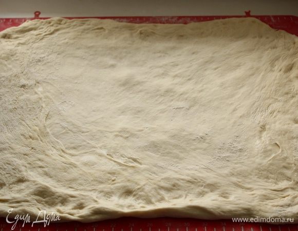 На обильно посыпанный мукой стол выкладываем тесто и руками, посыпая мукой сверху, формируем большой прямоугольник. 
