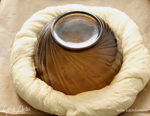 Аккуратно свернуть прямоугольник в рулет, после чего несколько раз перекрутить его как верёвку . Противень с бумагой для выпекания, немного посыпем мукой, в центр поставим что-нибудь круглое.  замкнуть кольцо, слегка скрепив концы рулета между собой.
Оставим  под полотенцем на 1 час.
