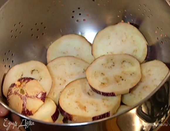 Нарезать баклажан поперек толстыми кружками, выложить в дуршлаг, пересыпать солью, оставить на 15–20 минут, затем промыть, дать воде стечь, просушить бумажным полотенцем и смазать со всех сторон оливковым маслом.