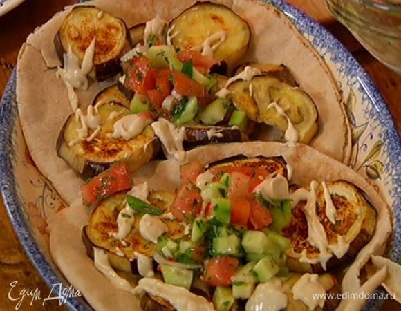 Теплые лепешки положить на блюдо, на них поместить баклажаны, сбрызнуть соусом, сверху выложить овощной салат.