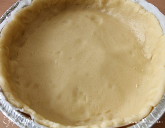 Достать тесто из холодильника, отделить примерно четверть для украшения. Остальное тесто раскатать в круг на бумаге для выпечки, перенести в форму, оформить бортик.