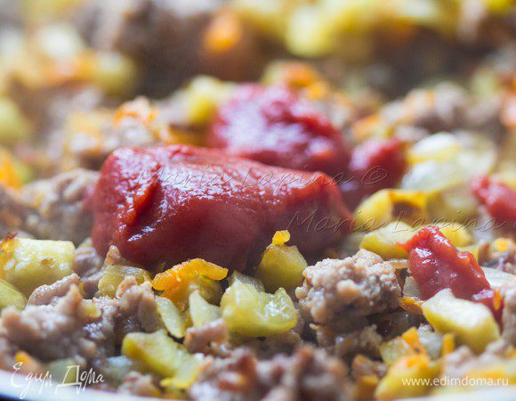 Добавляем томатную пасту и фарш. Солим, перчим и добавляем сухие травы. Наливаем около 150 мл. чистой воды или бульона, уменьшаем огонь, накрываем крышкой и томим 15 минут. Если вода будет слишком быстро выпариваться, добавить ещё. Соус должен получиться густым и влажным.