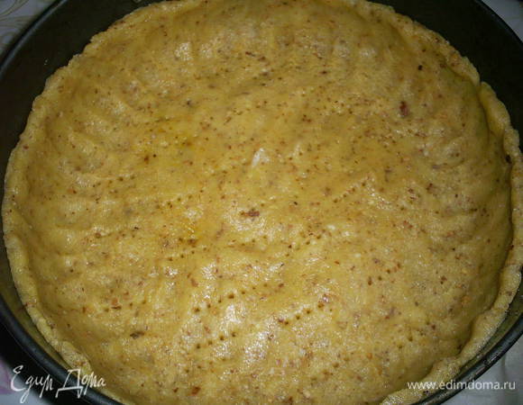 Возвращаемся к нашему тесту. Руками распределяем тесто по форме диаметром 22 см, дно которой выстелено бумагой, формируем высокие бортики. Дно густо накалываем вилкой.