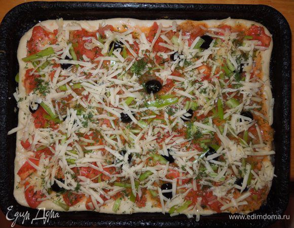 Выложить тесто на противень смазанным оливковым маслом, оставить края теста немного приподнятыми. Выложить на тесто приготовленный томатный соус, сверху распределить нарезанный перец и маслины, посыпать мелко нарезанным чесноком. Пиццу сверху посыпать тертым сыром пармезаном. 
Хорошо прогреть духовку и выпекать пиццу при температуре 210 градусов примерно 30 мин.
