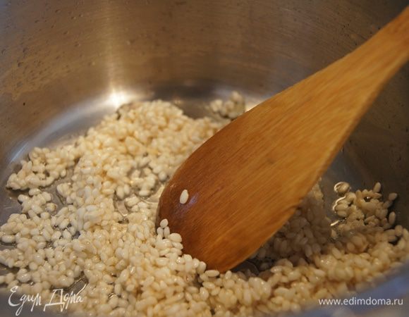 Лук удалить, насыпать в кастрюльку рис, помешивая обжарить его до прозрачности 1 минуту.