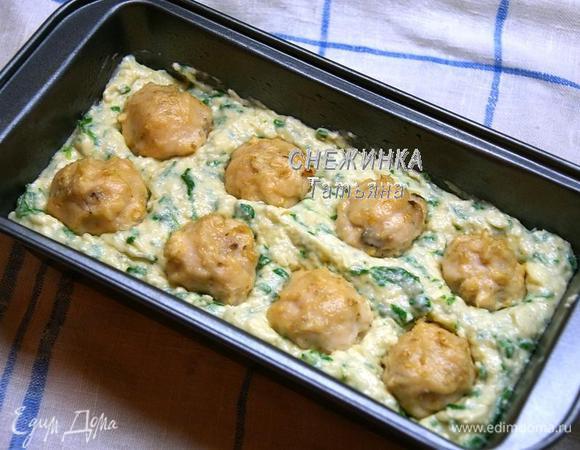 Прямоугольную форму для кекса смазываем маслом. Выкладываем половину теста. Кладём куриные шарики, немного вдавливая в тесто.