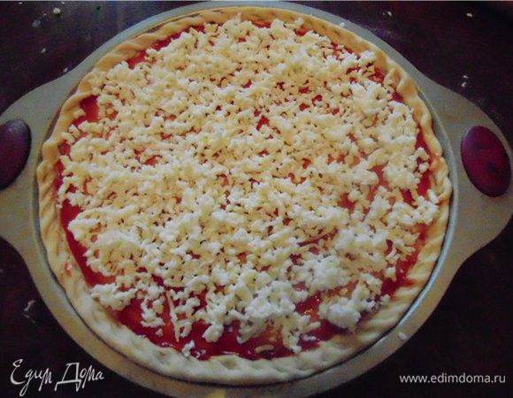 Смазываем пиццу томатным соусом. Сверху выкладываем натертую на крупной терке моцареллу.