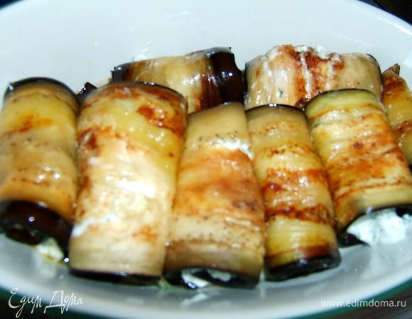 На каждый кусочек баклажана положить чайную ложку начинки и скатать в рулетики.