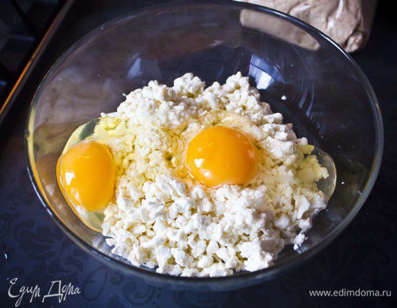 Положите творог в миску и вбейте туда 2 яйца.
