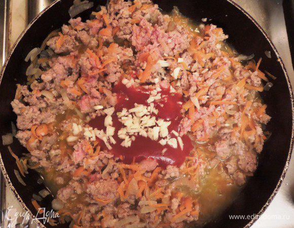 Разогреть на сковороде смесь оливкового и сливочного масла, затем обжарить говяжий фарш, обжарить также морковь и лук, добавить томатную пасту и  измельченный чеснок. Посолить и поперчить, тушить на медленном огне 10 мин. 

