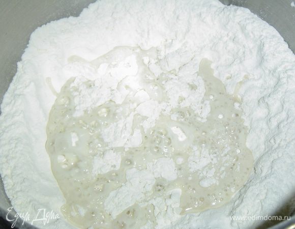 Муку просеиваем в миску, в центре делаем углубление, выливаем дрожжи, добавляем соль и перемешиваем. 