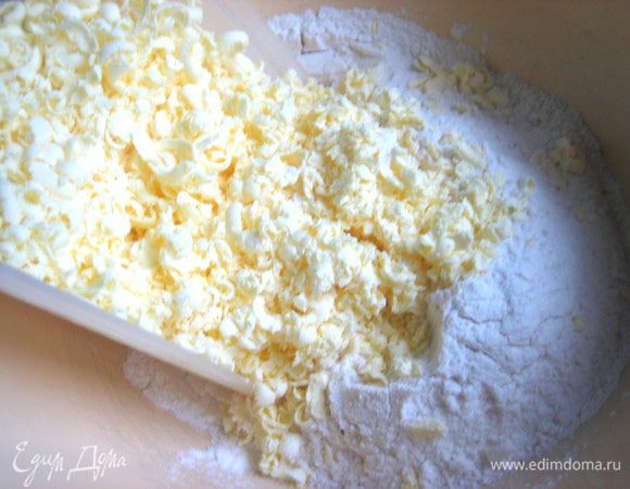 В просеянную муку натираем замороженное масло на тёрке.